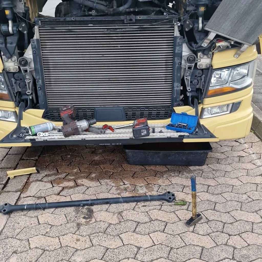 Fachgerechte Demontage des Scania Kühlers auf dem Parkplatz, Kühlmittel wird umweltgerecht in einer Spezialwanne aufgefangen