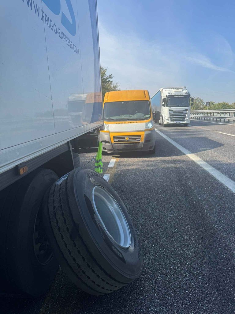 Abmontiertes Rad neben dem Auflieger, dahinter der Servicewagen auf dem Standstreifen in Italien